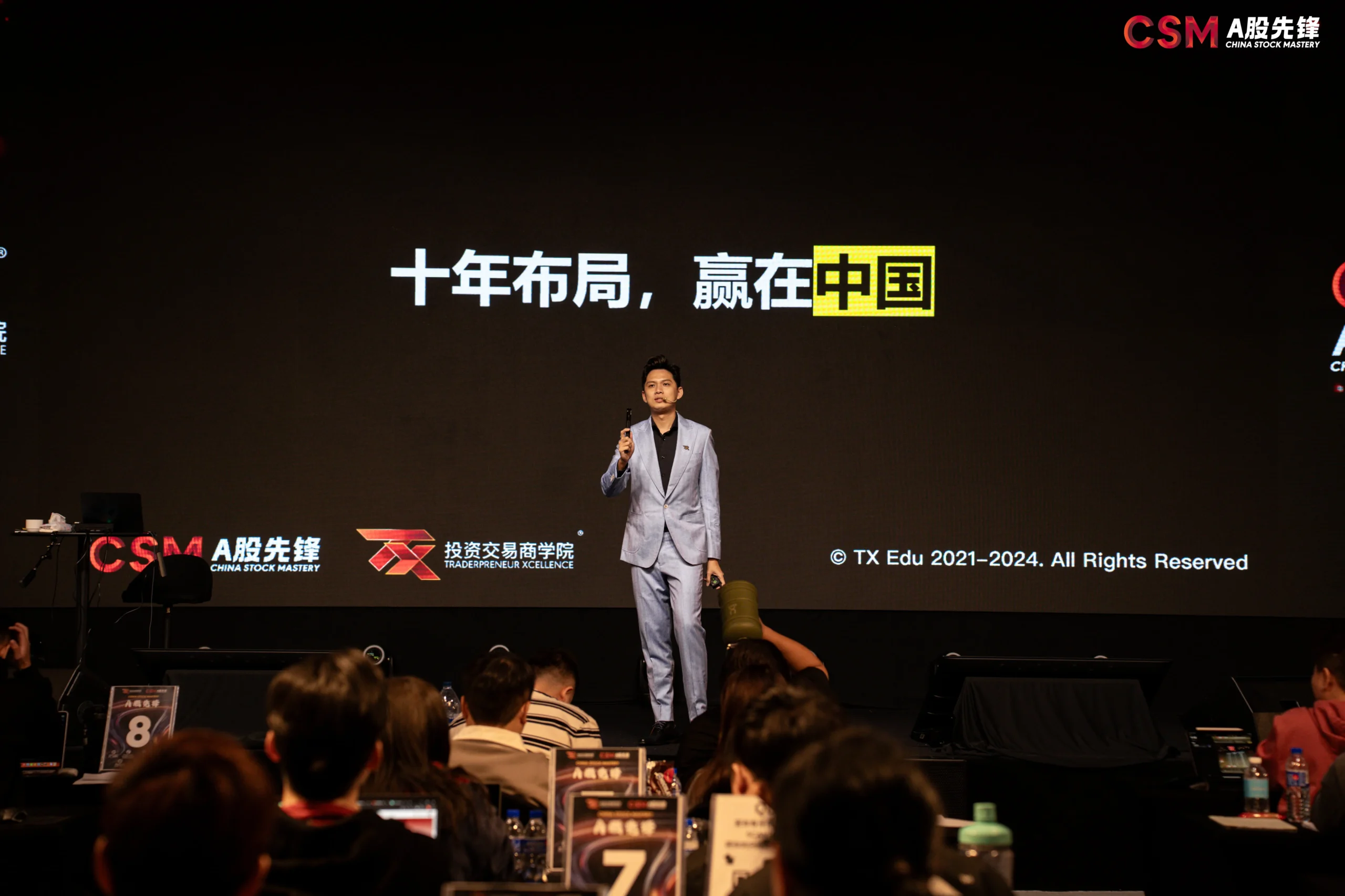 Speaker on stage at a China Stock Mastery seminar under the slogan 十年布局,赢在中国