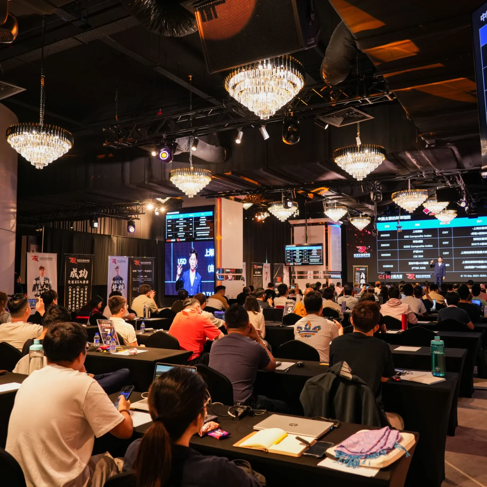 Students taking notes during a TX Academy trading class, with live market data on screens